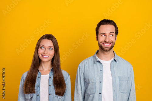 Photo of confident dreamy sister brother dressed denim shirts looking empty space isolated yellow color background