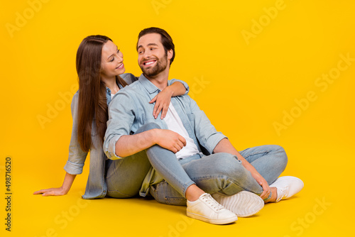 Portrait of two attractive cheerful cute people soulmate sitting hugging romance isolated over bright yellow color background