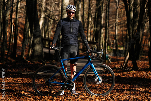 Portrait of cyclist in outfit, wearing helmet and goggles on the forest.