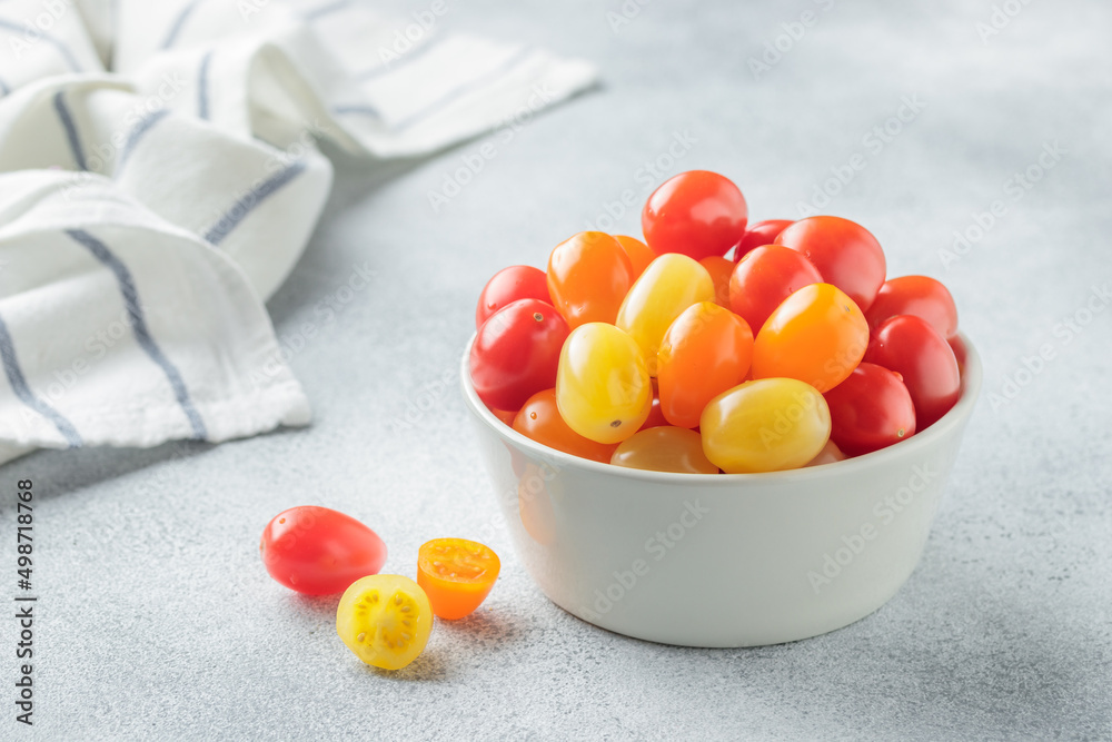 Yellow, orange and red cherry tomatoes in a white bowl Yellow, orange and red cherry tomatoes in a white bowl