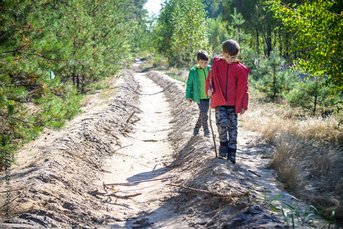 Two preschool children exploring forest, in autumn clothing, pla