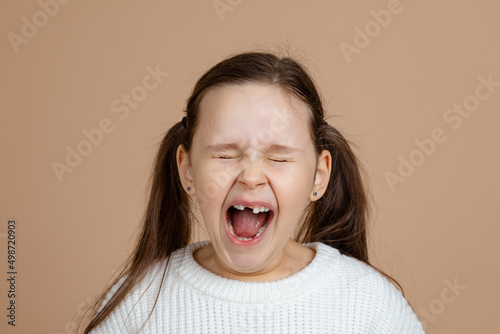 Tableau sur toile Portrait of young furious angry girl with long dark hair in pink, white sweater