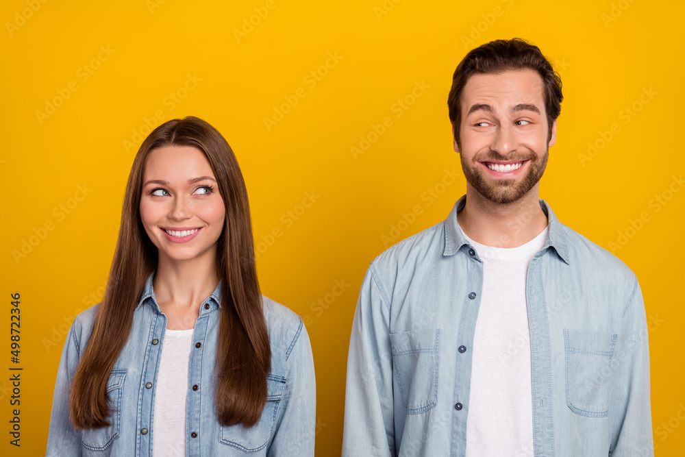 Photo of tricky funny husband wife wear jeans shirts looking each other eyes isolated yellow color background Photo of tricky funny husband wife wear jeans shirts looking each other eyes isolated yellow color background