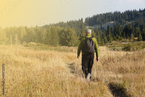 a man goes hiking with a backpack on a trail, rear view