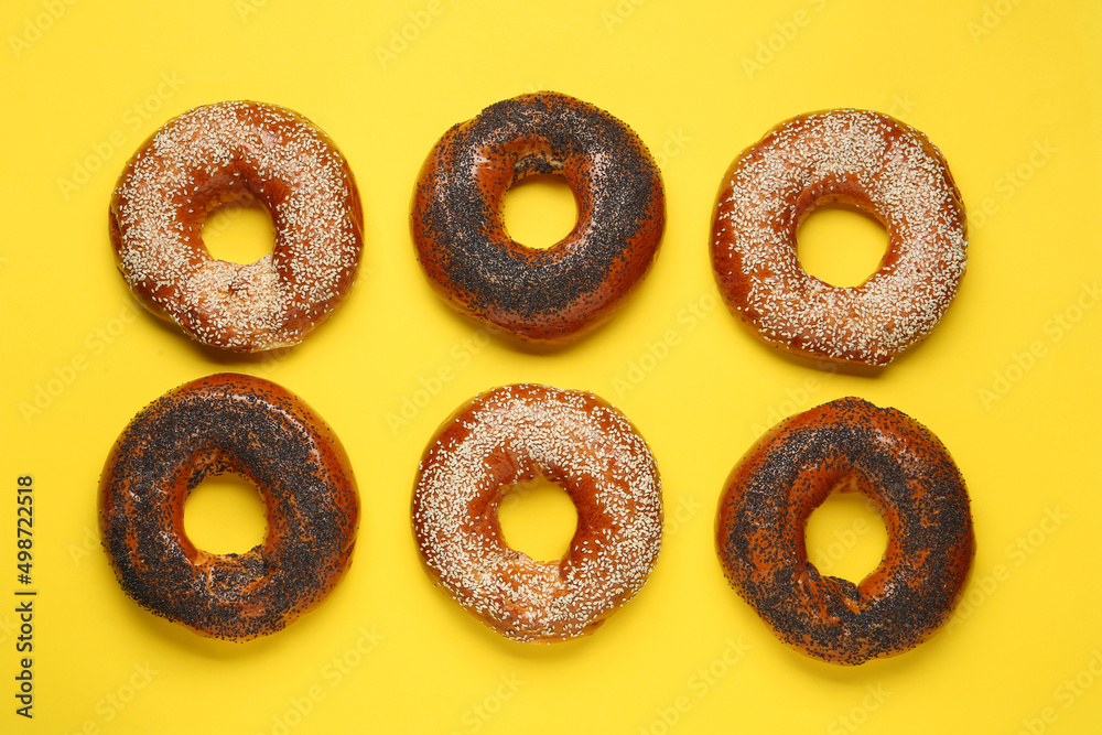 Many delicious fresh bagels on yellow background, flat lay Many delicious fresh bagels on yellow background, flat lay