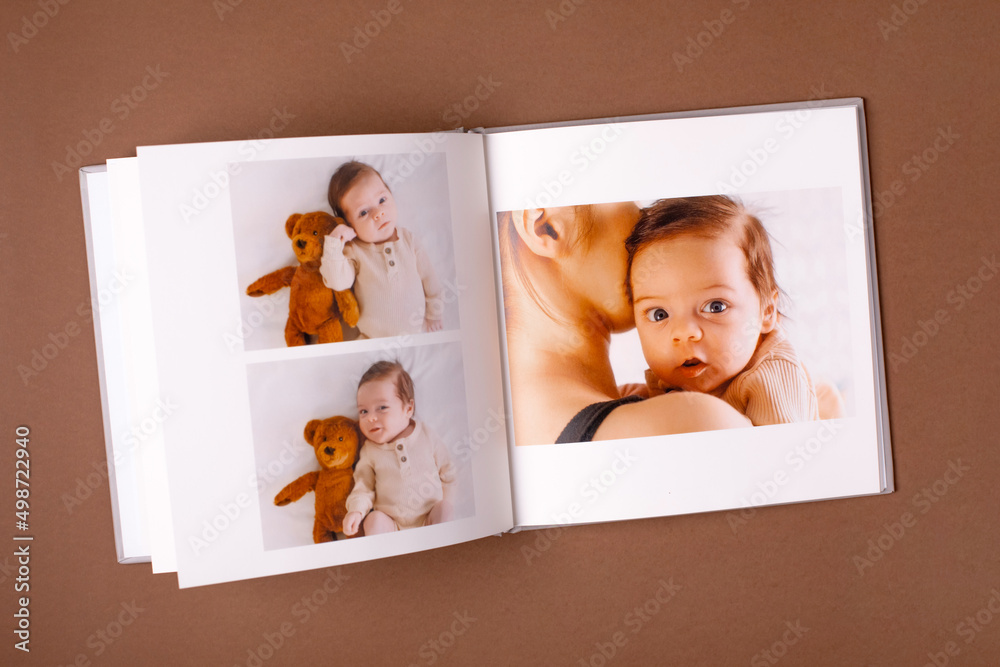 Baby's photo book on brown background . Children's emotional portrait.Cute toddler boy Baby's photo book on brown background . Children's emotional portrait.Cute toddler boy
