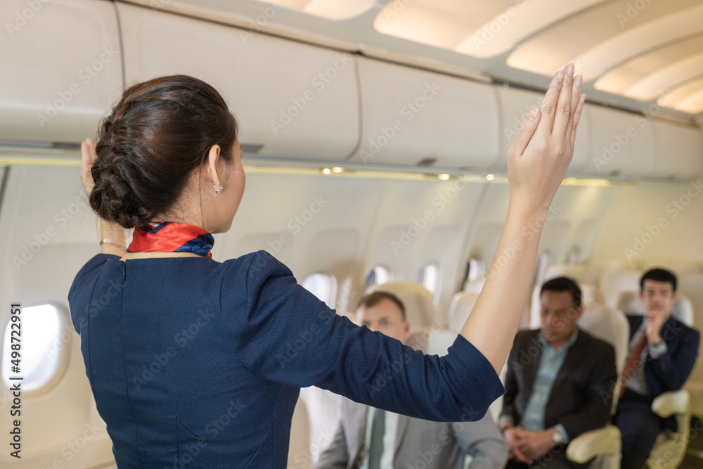 Back view of Flight attendant woman demonstration about safety to the passenger while during the flight... Back view of Flight attendant woman demonstration about safety to the passenger while during the flight...