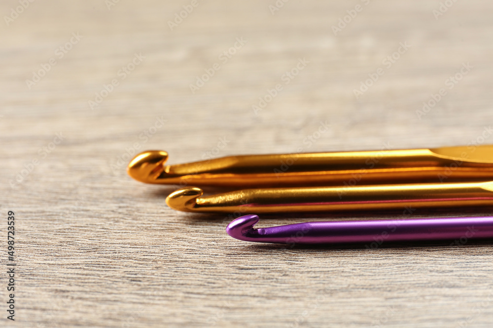 Many crochet hooks on wooden table, closeup