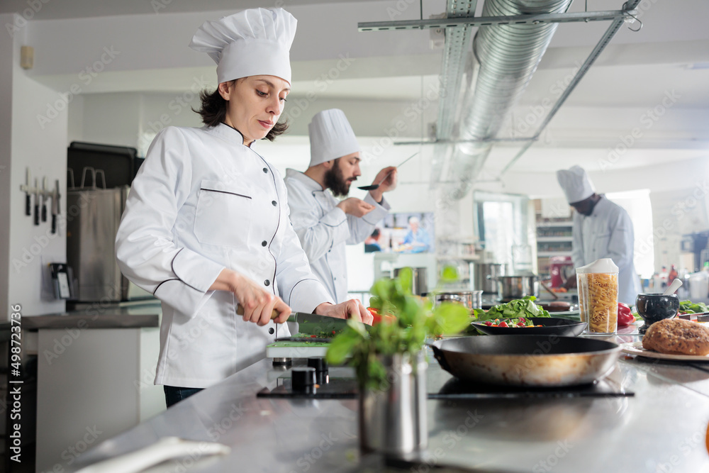 Sous chef preparing fresh vegetable garnish for gourmet dish served at dinner service in restaurant. Gastronomy expert chopping vegetables while cooking food for fine dining in professional kitchen