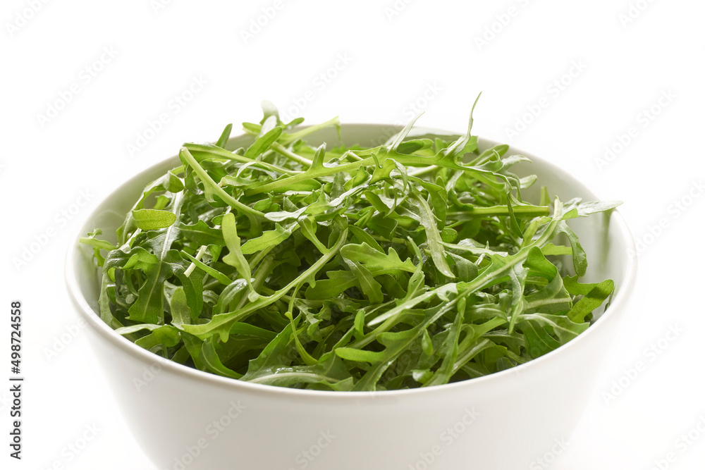 Fresh green arugula or rucola leaves in a white bowl isolated on a white background. Top view on Eruca Vesicaria, a plant used as a salad vegetable. Fresh green arugula or rucola leaves in a white bowl isolated on a white background. Top view on Eruca Vesicaria, a plant used as a salad vegetable.