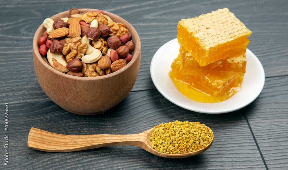 assortment of nuts and assorted dried citrus fruits and fresh floral honeycomb honey and pollen on kitchen wooden board. useful vitamin food for the human body assortment of nuts and assorted dried citrus fruits and fresh floral honeycomb honey and pollen on kitchen wooden board. useful vitamin food for the human body