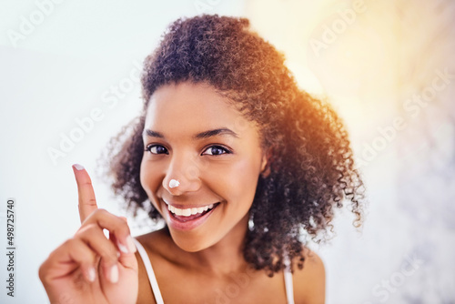 My skin care routines got me covered. Shot of an attractive young woman applying moisturizer to her nose in the bathroom at home.