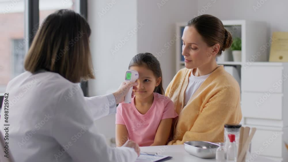 medicine, healthcare and pediatry concept - mother with sick little daughter and doctor measuring temperature with infrared forehead thermometer at clinic medicine, healthcare and pediatry concept - mother with sick little daughter and doctor measuring temperature with infrared forehead thermometer at clinic