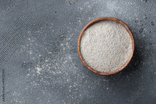 Rye flour in a wooden bowl top view on a grey concrete background