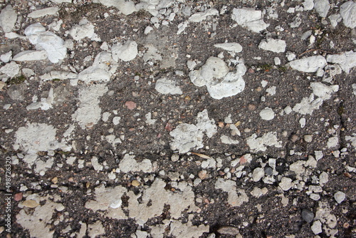 Fragment of an old road with cracked asphalt, stones and moss. Background image.