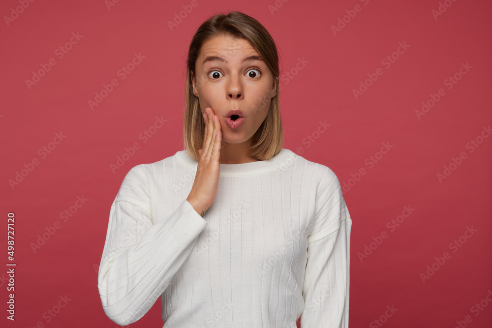 Studio portrait of young female student posing over red background, looking into camera with shocked, surprised facial expression. Studio portrait of young female student posing over red background, looking into camera with shocked, surprised facial expression.