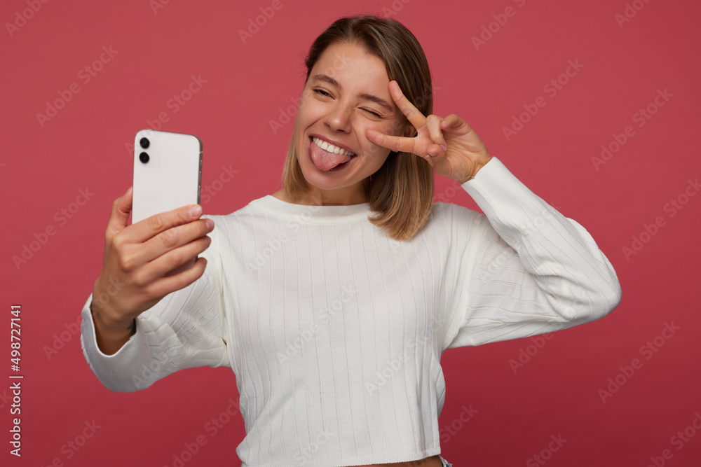 Studio portrait of young female student posing over red background, have a video call Studio portrait of young female student posing over red background, have a video call