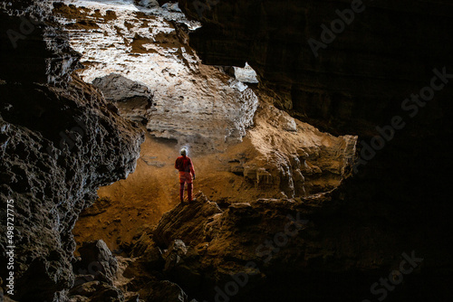 Caver man is looking through the cave gallery; speleologist photo