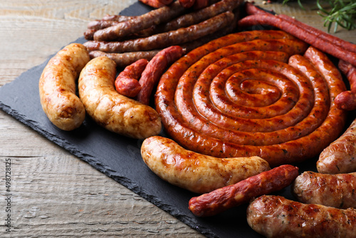 Different delicious sausages on wooden table. Assortment of beer snacks