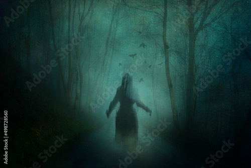 A horror concept of a ghostly woman in a dress. Haunting a forest road on a spooky winters night. With a grunge, textured edit.