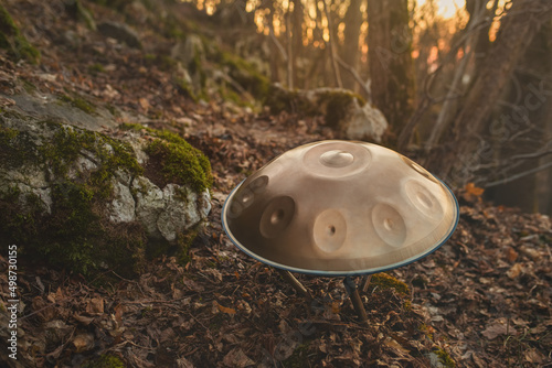 Musical instrument handpan placed on a stand in the forest at sunset. It is also known as a hang or pantam.