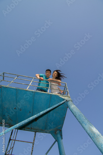 A man and a woman - a couple in love on a metal structure against a blue sky