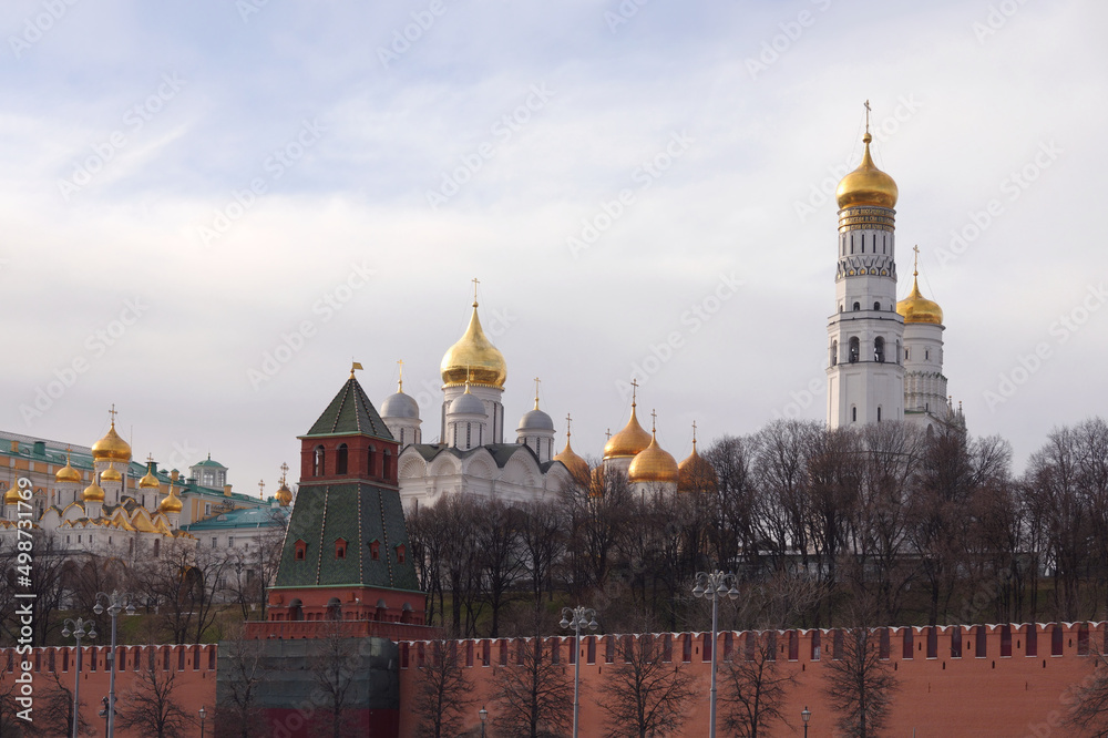 Ivan the Great Bell Tower, Cathedral of the Archangel and Cathedral of the Annunciation with golden cupolas behind the Kremlin wall view from embankment of the Moscow river front view