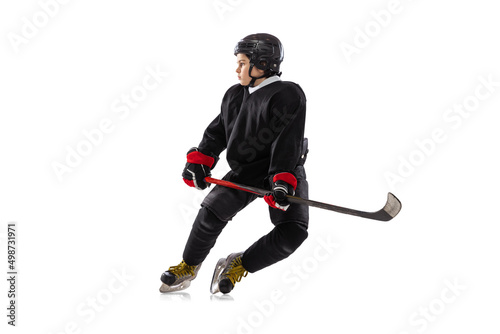 Dynamic portrait of kid, hockey player in black sportswear and helmet training isolated over white studio background