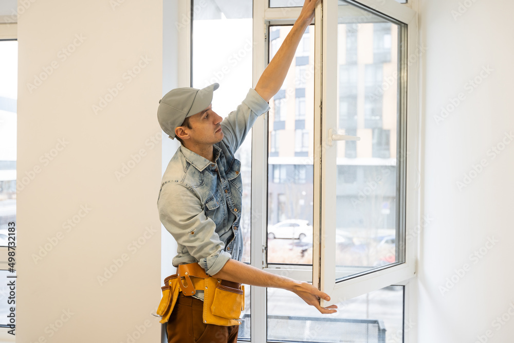 Construction worker installing window in house Construction worker installing window in house