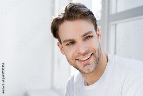 portrait of positive man smiling while looking away at home.