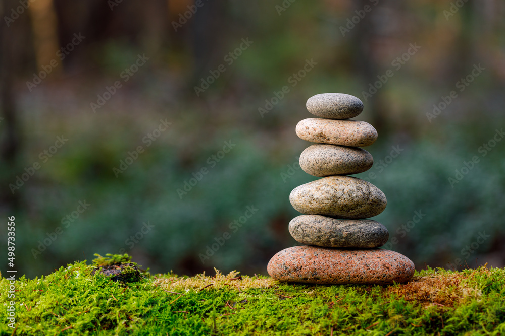 Pyramid stones balance on old mossy fallen tree. Stone pyramid in focus. Forest background blurred Pyramid stones balance on old mossy fallen tree. Stone pyramid in focus. Forest background blurred