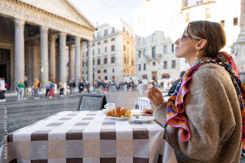 Photography Woman having breakfast with croissant and coffee at outdoor cafe near famous Pantheon temple in Rome