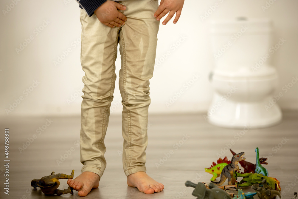 Little toddler child, boy, pee in his pants while playing with toys, child  distracted and forget to go to the toilet Stock Photo