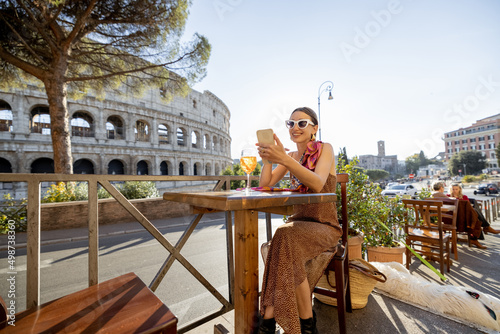 Photography Woman drinking Spritz Aperol at outdoor cafe near Coliseum, the most famous landmark in Rome
