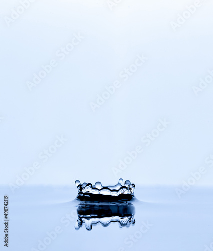 Splash and crown on white background. Reflection on the surface of the water.