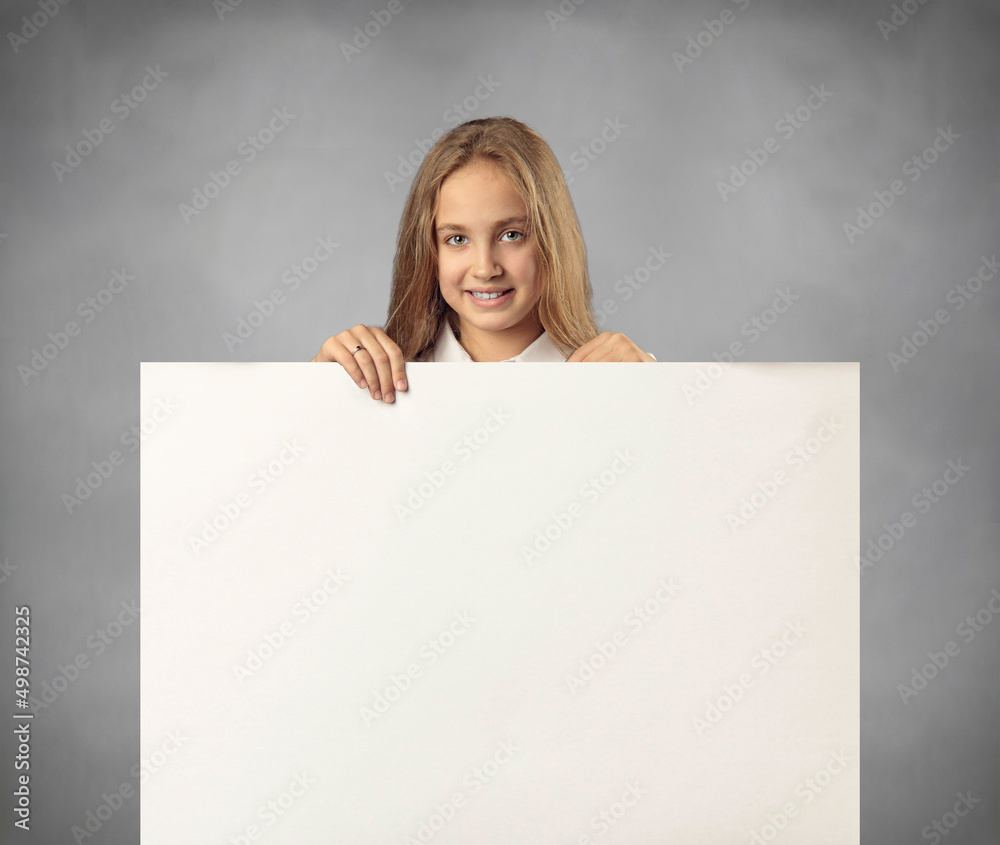 Intresting Offer. Happy Casual Blonde Girl Peeping Out The Side Of White Advertisement Board For Text Or Design. Smiling Cheerful Teenage Holding Billboard, Looking At Camera Intresting Offer. Happy Casual Blonde Girl Peeping Out The Side Of White Advertisement Board For Text Or Design. Smiling Cheerful Teenage Holding Billboard, Looking At Camera