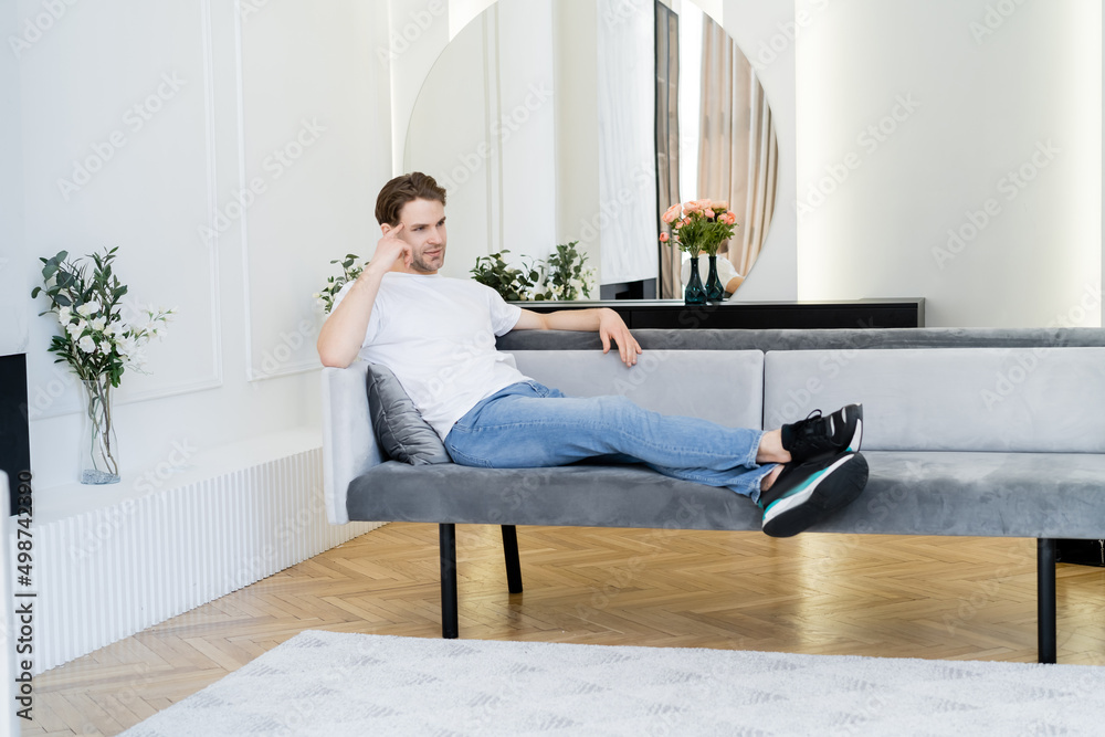 full length view of dreamy man resting in living room decorated with flowers. full length view of dreamy man resting in living room decorated with flowers.
