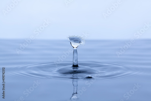 Splash and umbrella on blue background. Reflection on the surface of the water.