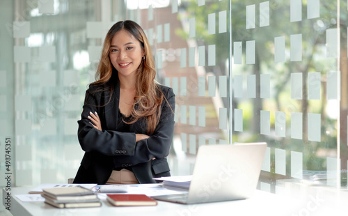 Image of a charming young Asian businesswoman standing at the office. Looking camera. © wichayada