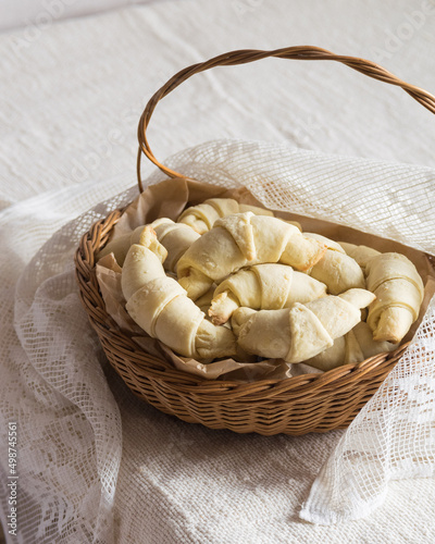 Russian homemade pastry rogaliki croissants in the rustic basket on light background. Selective focus