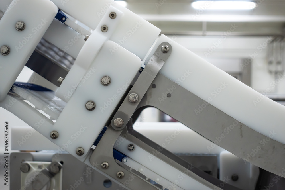 Modular belt conveyor in a food processing plant. A close-up of the machine components. Artificial lighting typical of such places