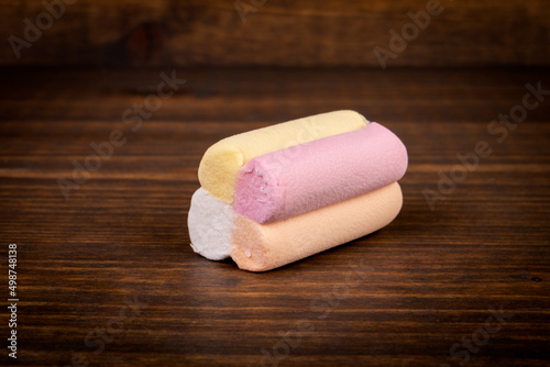 Colorful piece of marshmallow on a brown textured wooden background