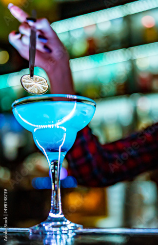 woman bartender hand at the bar or pub to prepare a cocktail Blue Lagoon