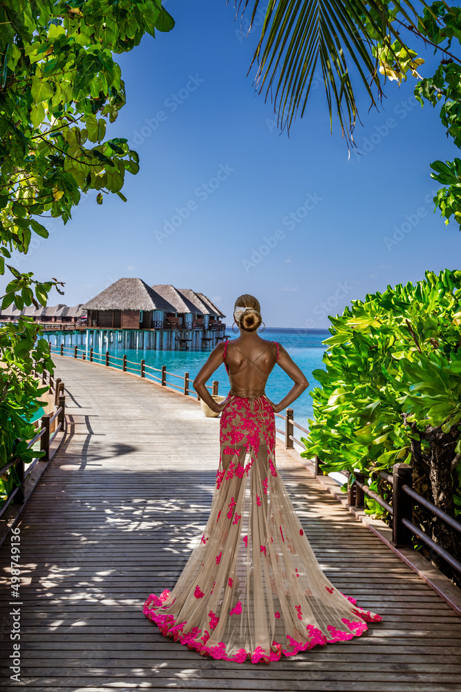 Luxury fashion. Elegant fashion model is posing outdoor. Stylish female model in long gown dress on the Maldives beach. Elegance. Classy woman in amazing dress on Maldives landscape. Couture. Vogue.