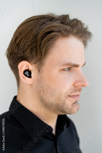 profile of young man listening music in wireless earphone isolated on grey.