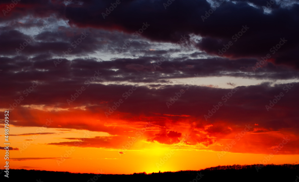 Abstract burning sky at sunset. Red clouds on the horizon are illuminated by evening sunlight