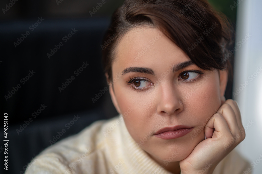 A dark-haired woman looking aside with a thoughtful view A dark-haired woman looking aside with a thoughtful view
