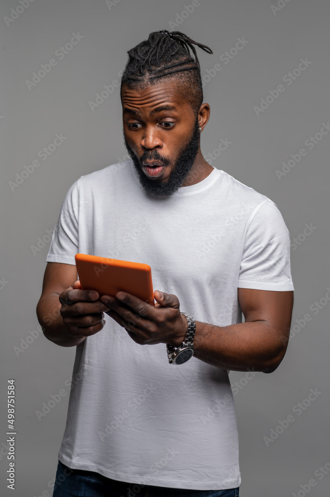 Shocked guy staring at the gadget in his hands Shocked guy staring at the gadget in his hands