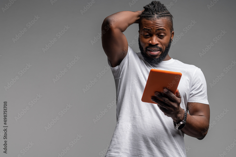 Shocked male looking at something on his gadget Shocked male looking at something on his gadget
