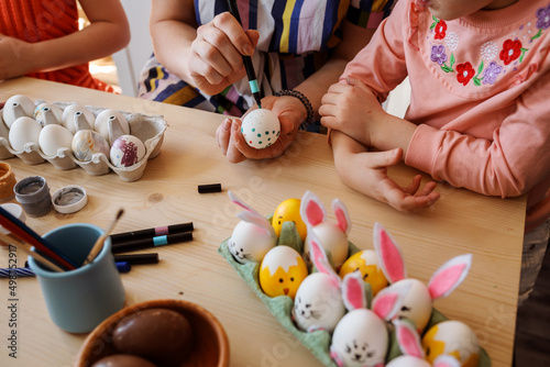 Close up view of woman painting easter eggs with her children at home, Easter holiday preparation.